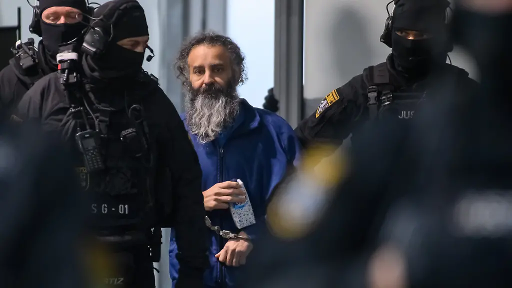 Justizbeamte-fuehren-den-Angeklagten-Taleb-al-Abdulmohsen-M-in-den-Gerichtssaal-des-temporaeren-Gerichtsgebaeude-des-Landgerichtes-Magdeburg-Dort-wurde-der-Prozess-gegen-den-Todesfahrer-vom-Magdeburger-Weihnachtsmarkt-fortgesetzt-Die-Generalstaatsanwaltschaft-wirft-dem-Mann-aus-Saudi-Arabien-versuchten-Mord-in-338-Faellen-vor-Am-20-Dezember-2024-raste-Taleb-al-Abdulmohsen-auf-dem-Magdeburger-Weihnachtsmarkt-in-eine-Menschenmenge-Fuenf-Frauen-und-ein-Kind-starben-bei-dem-Anschlag-mehr-als-300-Menschen-wurden-verletzt