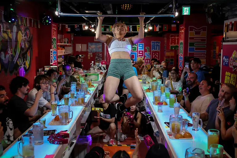 Yuka-Moriya-30-a-staffer-at-Muscle-Girls-a-fitness-themed-bar-does-pull-ups-on-a-metal-bar-suspended-from-the-ceiling-as-part-of-a-performance-for-customers-in-Tokyo-Japan-July-25-2025-With-its-challenge-to-Japan-s-conventional-ideals-of-feminine-beauty-Muscle-Girls-which-opened-in-mid-2020-draws-about-100-customers-on-average-each-day-the-majority-of-them-foreign-tourists-and-has-gone-viral-on-social-media-REUTERS-Kim-Kyung-Hoon-SEARCH-KYUNG-HOON-MUSCLE-GIRLS-FOR-THIS-STORY-SEARCH-WIDER-IMAGE-FOR-ALL-STORIES