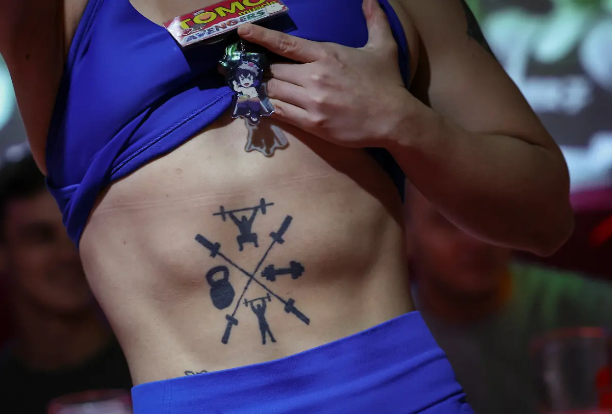 Tomomi-Matsumoto-35-a-staffer-at-Muscle-Girls-a-fitness-themed-bar-lifts-her-shirt-to-show-customers-a-tattoo-on-her-torso-in-Tokyo-Japan-September-11-2025-At-Muscle-Girls-Japan-s-only-female-fitness-themed-bar-about-30-young-women-passionate-about-workouts-and-bodybuilding-entertain-customers-and-flaunt-their-brawny-physiques-REUTERS-Kim-Kyung-Hoon-SEARCH-KYUNG-HOON-MUSCLE-GIRLS-FOR-THIS-STORY-SEARCH-WIDER-IMAGE-FOR-ALL-STORIES