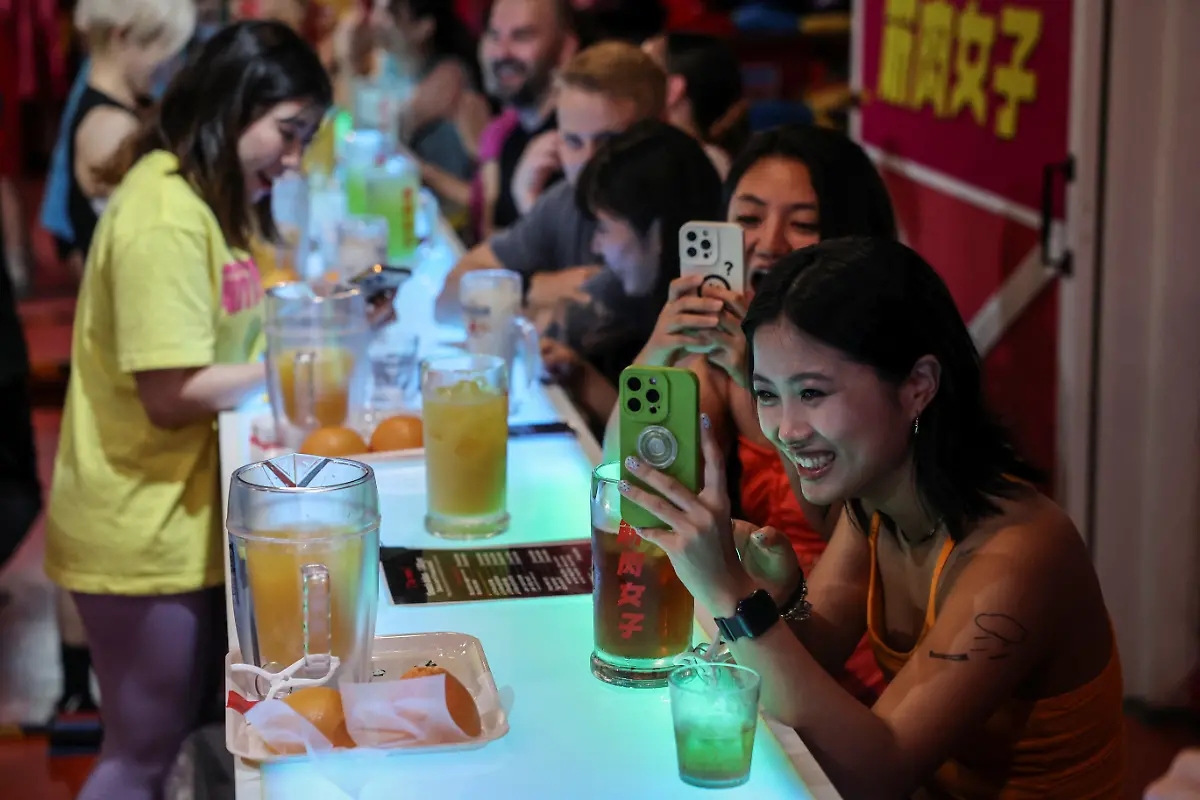 Female-customers-from-China-take-photos-during-a-performance-at-Muscle-Girls-a-fitness-themed-bar-in-Tokyo-Japan-July-25-2025-At-Muscle-Girls-Japan-s-only-female-fitness-themed-bar-about-30-young-women-passionate-about-workouts-and-bodybuilding-entertain-customers-and-flaunt-their-brawny-physiques-REUTERS-Kim-Kyung-Hoon-SEARCH-KYUNG-HOON-MUSCLE-GIRLS-FOR-THIS-STORY-SEARCH-WIDER-IMAGE-FOR-ALL-STORIES