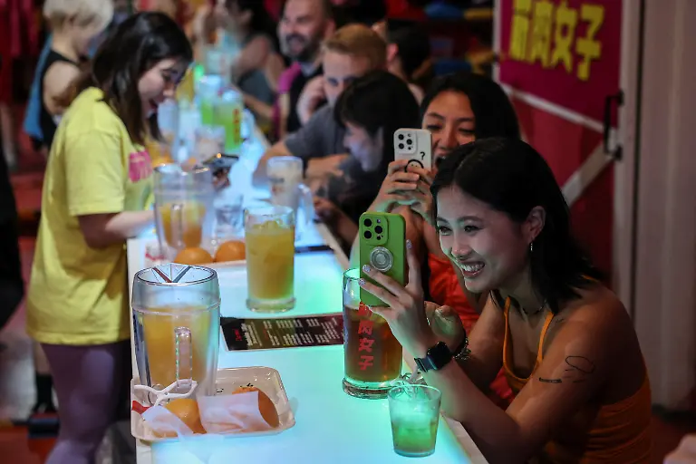 Female-customers-from-China-take-photos-during-a-performance-at-Muscle-Girls-a-fitness-themed-bar-in-Tokyo-Japan-July-25-2025-At-Muscle-Girls-Japan-s-only-female-fitness-themed-bar-about-30-young-women-passionate-about-workouts-and-bodybuilding-entertain-customers-and-flaunt-their-brawny-physiques-REUTERS-Kim-Kyung-Hoon-SEARCH-KYUNG-HOON-MUSCLE-GIRLS-FOR-THIS-STORY-SEARCH-WIDER-IMAGE-FOR-ALL-STORIES
