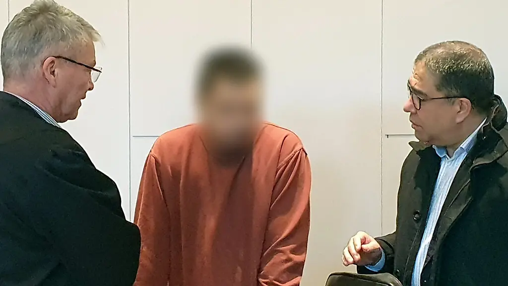 Der-Angeklagte-M-steht-im-Landgericht-beim-Prozess-um-den-toedlichen-Messerangriff-in-der-Krefelder-Filiale-einer-Modekette-zwischen-seinem-Verteidiger-Joerg-Hintzen-l-und-einem-Dolmetscher-Der-mann-muss-sich-wegen-der-Toetung-einer-Textilgeschaeft-Beschaeftigten-mit-25-Messerstichen-verantworten