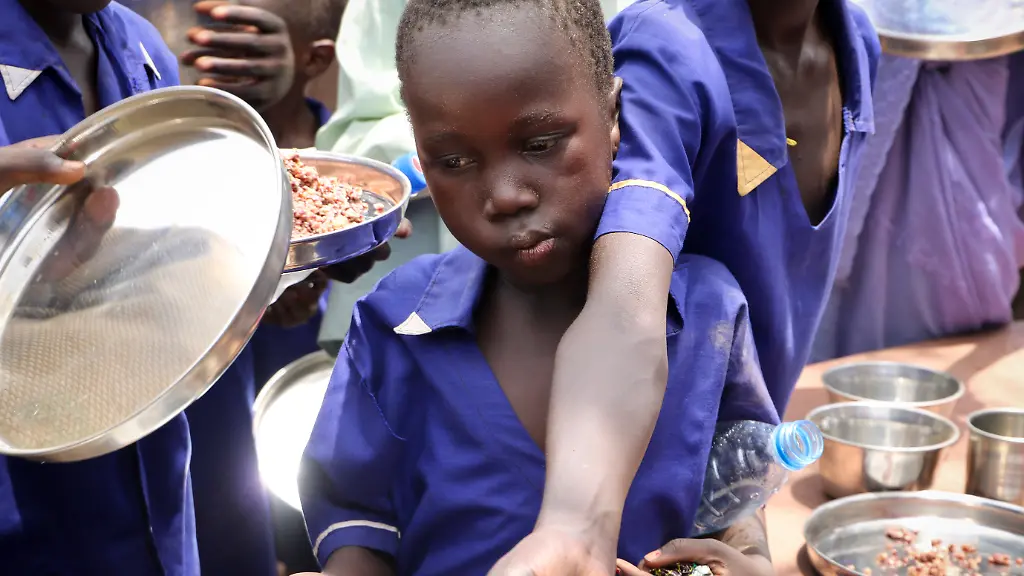 In-this-photo-taken-Tuesday-March-26-2019-children-push-their-plates-out-to-receive-a-portion-of-cooked-grains-during-a-lunchtime-feeding-program-initiative-launched-by-UNICEF-and-the-World-Food-Programme-with-the-aim-of-providing-daily-meals-to-75-000-children-in-Aweil-Northern-Bahr-el-Ghazal-state-in-South-Sudan-Human-rights-activist-Mia-Farrow-spoke-to-The-Associated-Press-as-she-visited-South-Sudan-again-in-her-new-role-as-envoy-for-the-International-Rescue-Committee-helping-the-aid-group-to-promote-a-global-initiative-to-change-the-way-humanitarian-organizations-approach-malnutrition