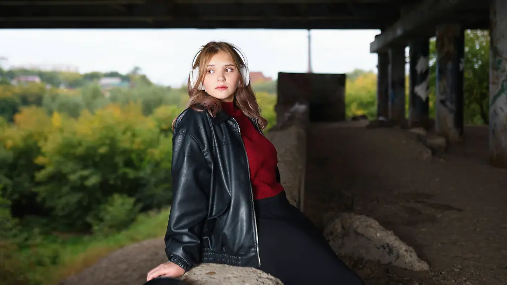 Young-woman-in-leather-jacket-and-headphones-under-bridge-in-ghetto-model-released-Symbolfoto-VCF00926