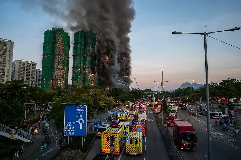 Hong-Kong-Building-Fire-Emergency-vehicles-parked-in-a-road-where-Smoke-and-flames-rise-as-a-major-fire-engulfs-several-residential-buildings-at-Wang-Fuk-Court-on-November-26-2025-in-Hong-Kong-Serval-residential-building-in-Wang-Fuk-Court-located-in-Tai-Po-District-caught-fire-today-the-Hong-Kong-Fire-Department-has-issued-the-No-5-fire-alarm-the-fire-at-local-time-1800-has-claimed-the-life-of-one-firefighter-and-three-other-people