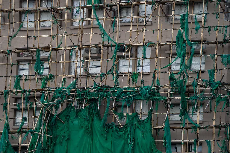 Ein-Baugeruest-aus-Bambusstangen-mit-zerstoerten-Schmutzfaengern-steht-an-einem-vom-Feuer-zerstoertem-Gebaeude