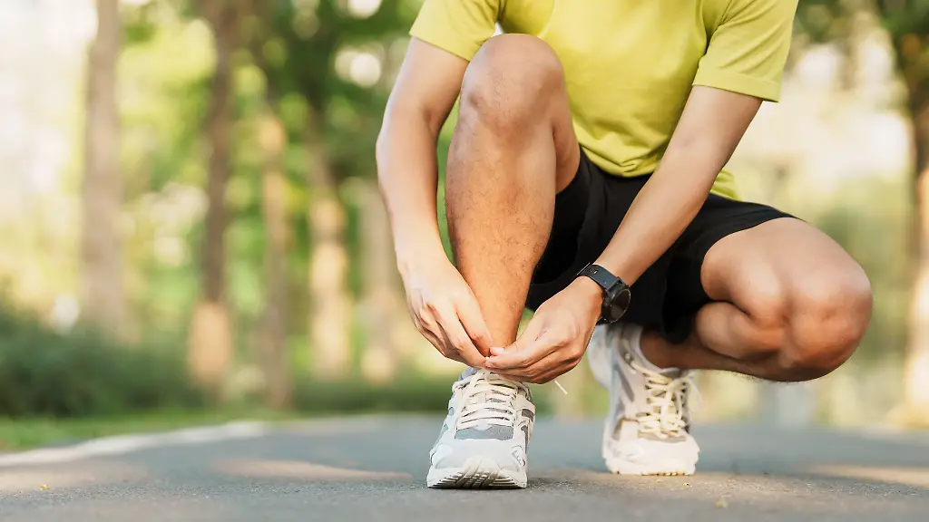 Laeufer-schnuert-sich-die-Laufschuhe-im-Park