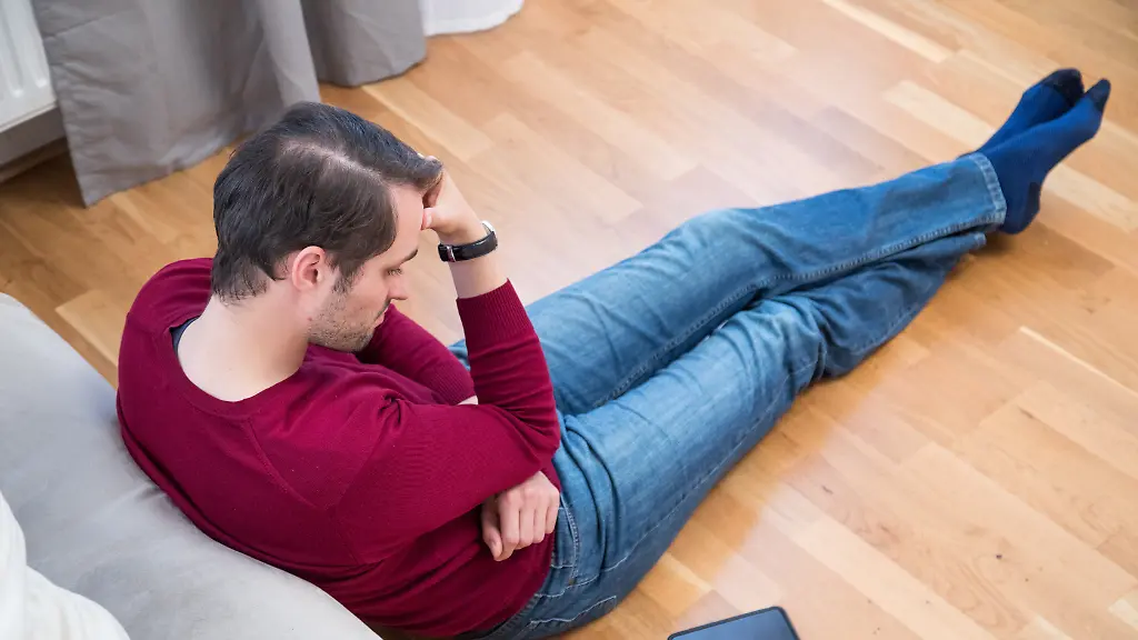 ILLUSTRATION-Ein-Mann-sitzt-am-13-09-2017-in-einer-Wohnung-in-Hamburg-auf-dem-Boden-und-schaut-auf-sein-Smartphone-das-auf-neben-ihm-auf-dem-Boden-liegt-gestellte-Szene