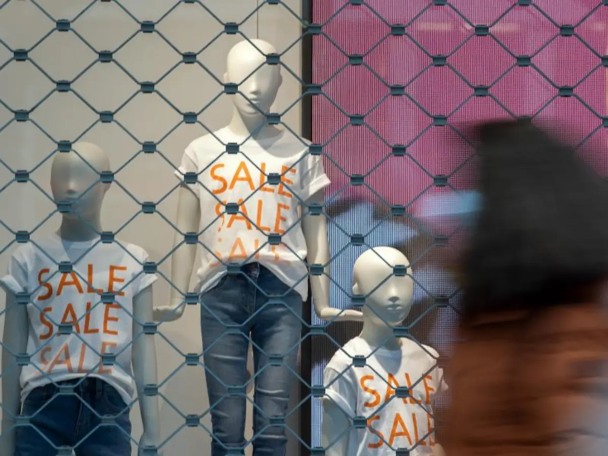 Hinter-geschlossenen-Sicherheitsgittern-stehen-Schaufensterpuppen-mit-Sale-T-Shirts