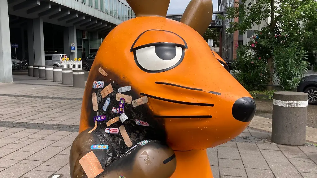 Nach-einem-mutmasslichen-Brandanschlag-auf-die-Maus-Figur-vor-dem-WDR-Gebaeude-in-Koeln-sind-mehrere-Pflaster-auf-der-verbrannten-Stelle-zu-sehen