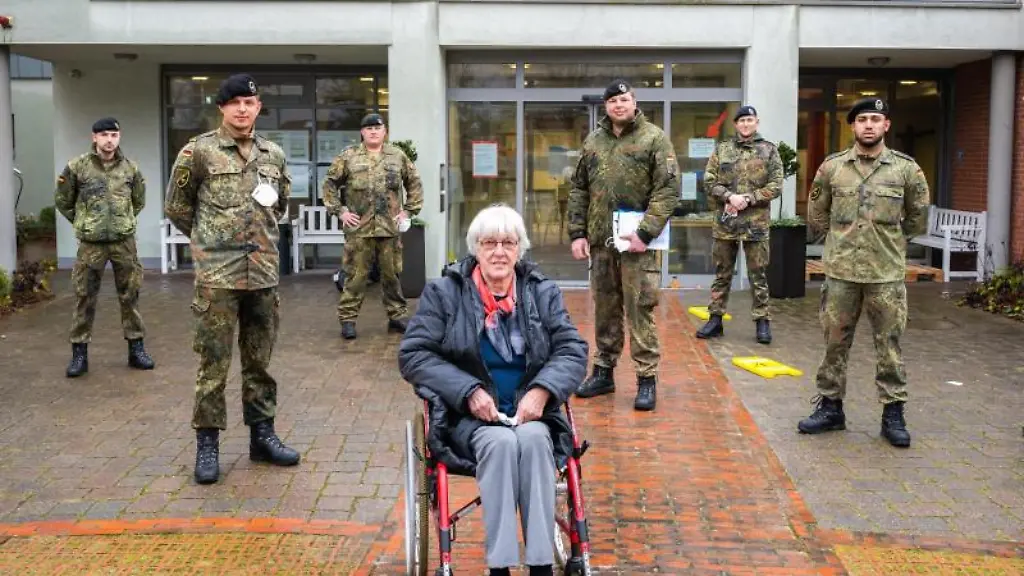 Bundeswehrsoldaten-stehen-vor-einem-Altenheim-hinter-einer-Bewohnerin