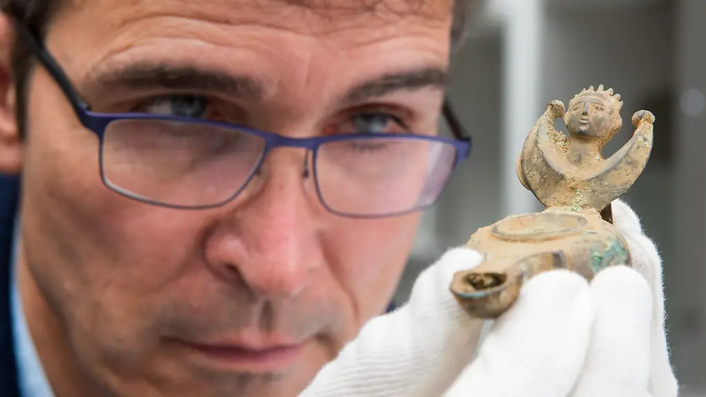 Augsburgs-Stadtarchaeologe-Sebastian-Gairhos-betrachtet-eine-antike-Oellampe-die-vor-wenigen-Jahren-in-Bayerns-aeltestem-Roemerlager-entdeckt-wurde