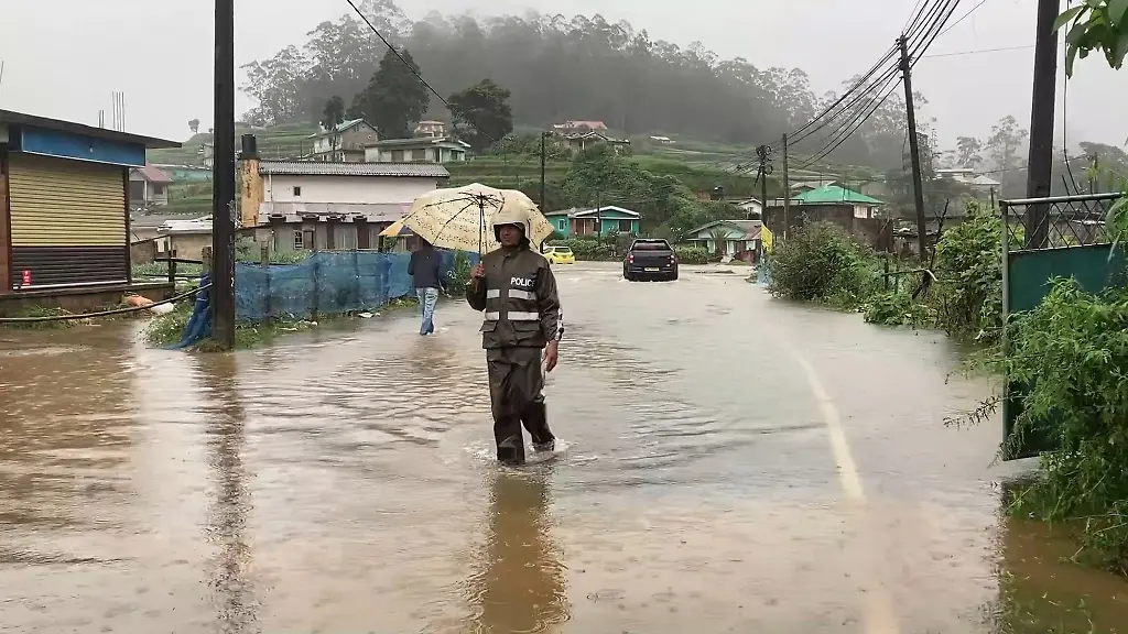 251127-COLOMBO-Nov-27-2025-Xinhua-This-photo-taken-with-a-mobile-phone-shows-a-police-officer-wading-through-floodwater-in-Nuwara-Eliya-District-Sri-Lanka-s-Central-Province-Nov-27-2025-Sri-Lanka-is-confronting-one-of-its-most-severe-weather-disasters-in-recent-years-as-days-of-heavy-rainfall-and-multiple-landslides-have-killed-31-people-left-14-missing-and-displaced-thousands-across-the-island-the-Disaster-Management-Center-DMC-said-on-Thursday-According-to-the-latest-situation-report-extreme-weather-has-affected-17-districts-impacting-1-158-families-and-4-008-individuals-The-DMC-said-10-people-have-been-injured-three-homes-have-been-completely-destroyed-and-381-houses-partially-damaged-At-least-131-people-have-been-relocated-to-temporary-safe-centers