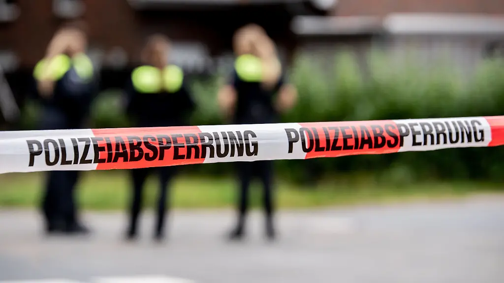 Polizisten-stehen-hinter-einem-mit-Flatterband-abgesperrten-Bereich-Ein-Mann-soll-seine-Kinder-und-seine-Partnerin-im-niedersaechsischen-Oldenburg-erschossen-haben-Anschliessend-soll-er-sich-selbst-getoetet-haben-teilte-die-Polizei-mit