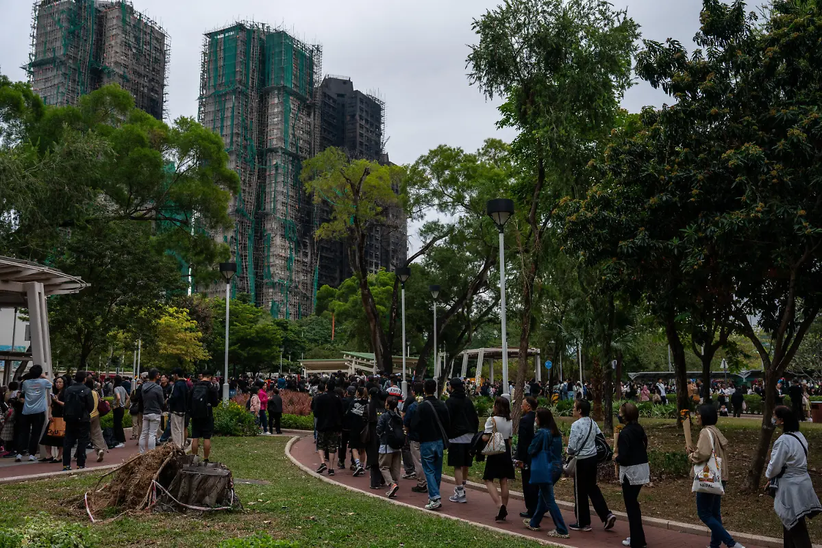 November-30-2025-Hong-Kong-Hong-Kong-Mourners-lining-up-to-lay-flowers-at-a-makeshift-memorial-near-Wang-Fuk-Court-housing-complex-in-Tai-Po-following-a-deadly-fire-on-November-30-2025-in-Hong-Kong