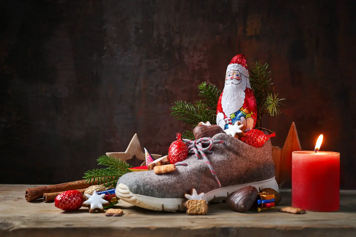6-Dezember-traditioneller-deutscher-Feiertag-St-Nikolaus-oder-Nikolaus-Schuh-gefuellt-mit-Suessigkeiten-Schokolade-Weihnachtsdekoration-und-eine-Kerze-dunkler-Hintergrund-copy-space-6-Dezember-traditioneller-deutscher-Feiertag-St-Nikolaus-oder-Nikolaus-Schuh-gefuellt-mit-Suessigkeiten-Schokolade-Weihnachtsdekoration-und-eine-Kerze-dunkler-Hintergrund-copy-space-LicenseRF-Copyright-xZoonar