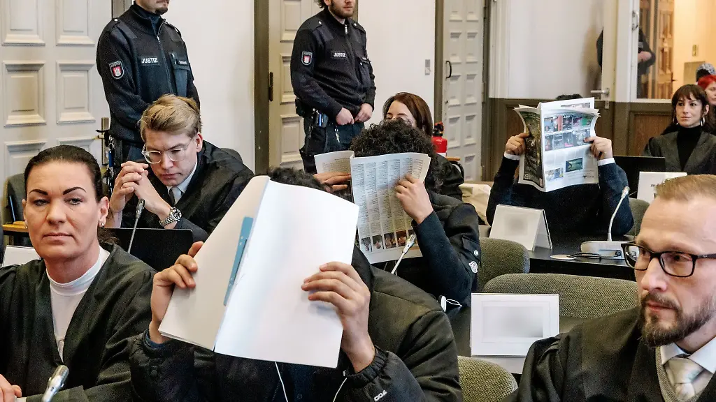 Die-Angeklagten-im-Prozess-verbergen-ihre-Gesichter-vor-den-Fotografen