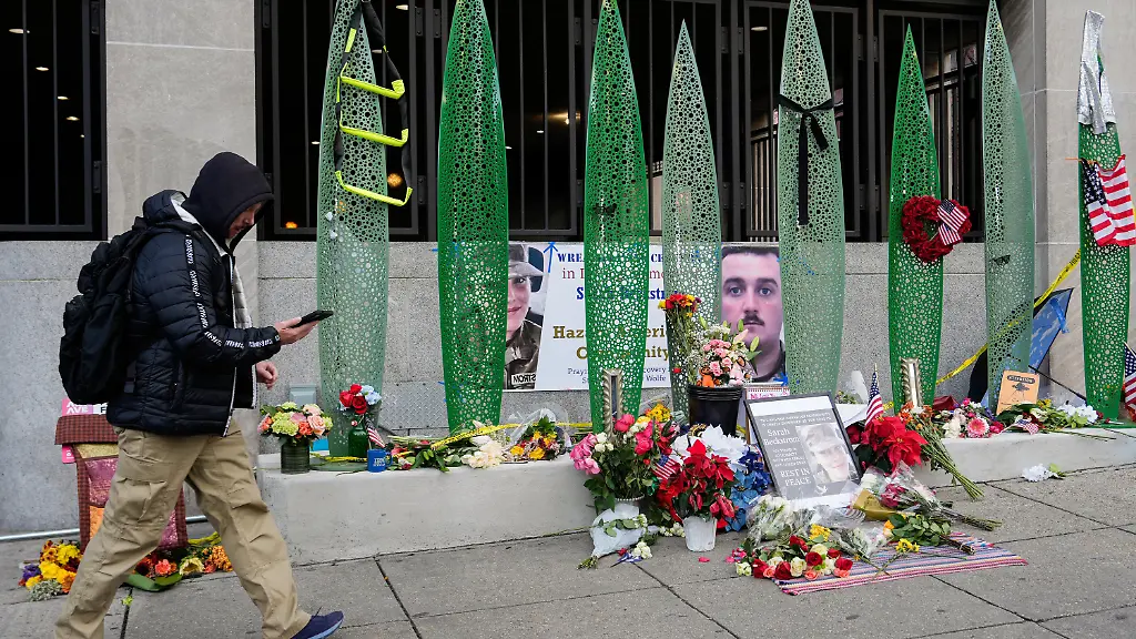 01-12-2025-USA-Washington-Eine-Person-geht-an-einer-behelfsmaessigen-Gedenkstaette-nach-Schuessen-auf-zwei-Nationalgardisten-ausserhalb-der-Farragut-West-Station-vorbei-in-der-Naehe-des-Ortes-an-dem-die-beiden-Nationalgardisten-erschossen-wurden