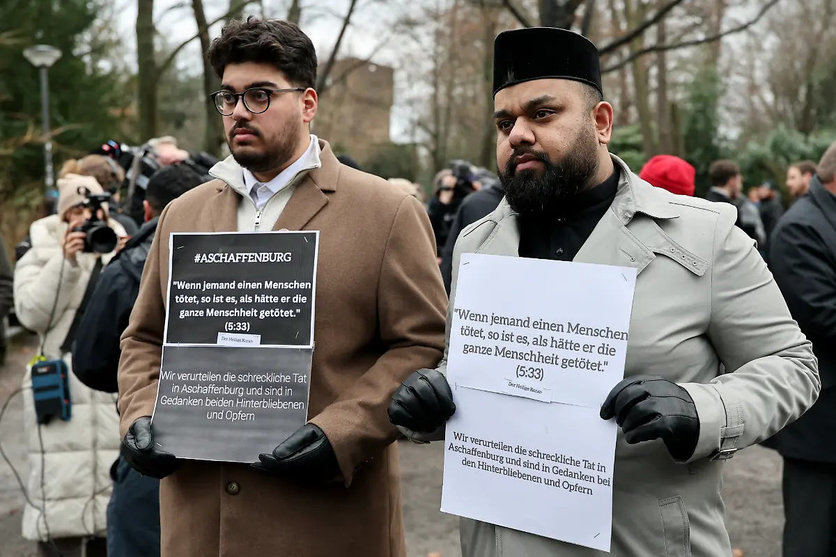 Zischan-Mehmood-r-Imam-von-Aschaffenburg-und-der-gleichnamige-Zischan-Mehmood-l-Mitglied-der-Gemeinde-stehen-mit-Trauerbekundungen-nach-einer-Kranzniederlegung-nach-dem-toedlichen-Angriff-in-einem-Park-In-einem-Park-in-Aschaffenburg-waren-am-Vortag-ein-zweijaehriger-Junge-und-ein-41-jaehriger-Mann-getoetet-sowie-weitere-Menschen-schwer-verletzt-worden