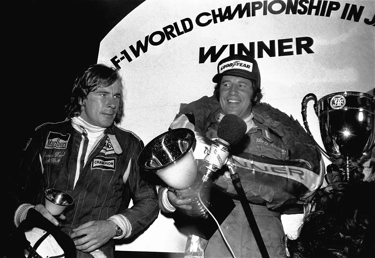 American-race-car-driver-Mario-Andretti-right-garlanded-with-laurel-and-holding-a-cup-speaks-into-a-microphone-while-Britain-s-James-Hunt-is-looking-on-after-the-Japan-Formula-One-Grand-Prix-at-Fuji-International-Speedway-here-October-24-1976-Andretti-won-the-race-but-won-the-world-driving-championship-with-a-69-point-one-point-edge-over-Austria-s-Niki-Lauda-who-withdrew-from-the-race-after-the-first-lap