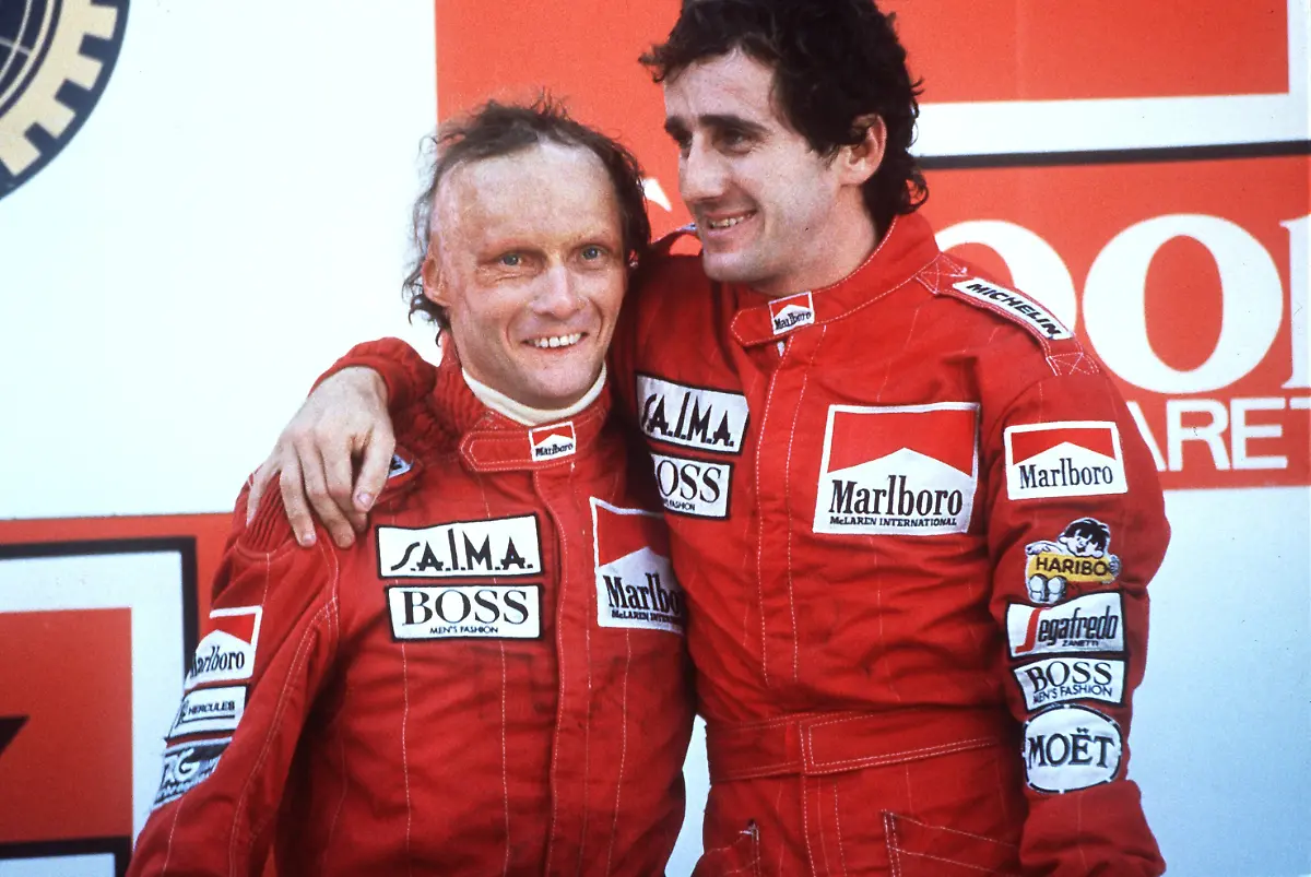 Der-oesterreichische-Formel-1-Rennfahrer-Niki-Lauda-l-mit-seinem-Teamkollegen-dem-Franzosen-Alain-Prost-am-21-10-1984-nach-seinem-Sieg-beim-Grand-Prix-im-portugiesischen-Estoril-Das-Formel-1-Finale-im-portugiesischen-Estoril-haette-spannender-nicht-sein-koennen-Erst-in-den-letzten-Runden-sicherte-sich-Niki-Lauda-durch-den-zweiten-Platz-hinter-seinem-Teamgefaehrten-Alain-Prost-den-Sieg-in-der-Gesamtwertung-und-somit-den-WM-Titel-1984