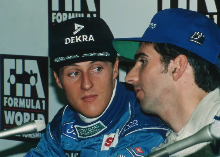 Damon-Hill-of-Britain-right-whispers-to-Michael-Schumacher-of-Germany-during-a-joint-press-conference-by-the-top-three-qualified-drivers-for-the-Japanese-Grand-Prix-at-the-Suzuka-Circuit-on-Nov-4-1994-Schumacher-kept-pole-position-while-Hill-took-second-position-on-the-grid