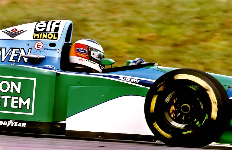 Michael-Schumacher-hat-die-Formel-1-Saison-1994-mit-einem-triumphalen-Erfolg-beim-Grossen-Preis-von-Brasilien-in-Interlagos-bei-Sao-Paulo-eroeffnet-Der-25jaehrige-aus-Kerpen-feierte-in-seinem-Benetton-Ford-am-27-03-1994-den-dritten-Grand-Prix-Sieg-seiner-Karriere-Der-Deutsche-bereitete-den-100000-Zuschauern-schon-eine-Enttaeuschung-als-er-den-Lokalmatadoren-und-WM-Favoriten-Ayrton-Senna-Williams-Renault-bereits-in-der-22-Runde-ueberholte-und-ihn-sicher-in-Schach-hielt-bevor-der-Brasilianer-nach-einem-Dreher-in-der-57-Runde-ausschied-Hinter-Schumacher-belegte-der-Brite-Damon-Hill-auf-Williams-Renault-Rang-zwei-mit-einer-Runde-Rueckstand-Dritter-wurde-Jean-Alesi-Frankreich-Ferrari