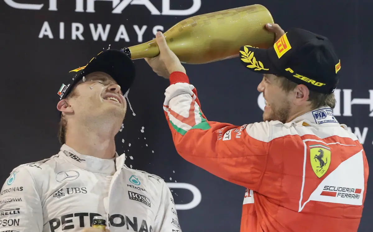 Third-place-Ferrari-driver-Sebastian-Vettel-of-Germany-sprays-rose-water-to-second-place-Mercedes-driver-Nico-Rosberg-of-Germany-on-the-podium-after-the-Emirates-Formula-One-Grand-Prix-at-the-Yas-Marina-racetrack-in-Abu-Dhabi-United-Arab-Emirates-Sunday-Nov-27-2016-Rosberg-was-12-points-ahead-of-his-teammate-Lewis-Hamilton-coming-into-the-title-showdown-and-only-needed-to-finish-third-even-if-Hamilton-won