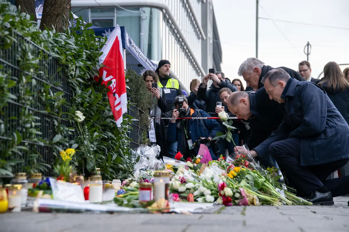 Bundeskanzler-Olaf-Scholz-SPD-Muenchens-Oberbuergermeister-Dieter-Reiter-SPD-und-Verkehrsminister-Volker-Wissing-parteilos-l-r-legen-weisse-Rosen-an-der-Stelle-nieder-wo-am-13-Februar-ein-Auto-in-eine-Ver-di-Demonstration-gerast-war-Nach-dem-Anschlag-mit-39-Verletzten-in-Muenchen-sind-noch-viele-Fragen-offen-Die-Ermittler-gehen-bislang-von-einem-islamistischen-Motiv-aus
