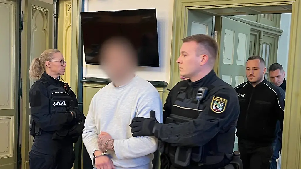 Der-angeklagte-Haeftling-2-v-l-wird-von-Justizbeamten-in-den-Gerichtssaal-im-Landgericht-gefuehrt-Er-soll-seine-Ehefrau-waehrend-eines-Besuchs-in-einer-sogenannten-Liebeszelle-in-der-Justizvollzugsanstalt-Burg-erwuergt-haben-Die-Staatsanwaltschaft-Stendal-wirft-dem-Haeftling-Totschlag-vor