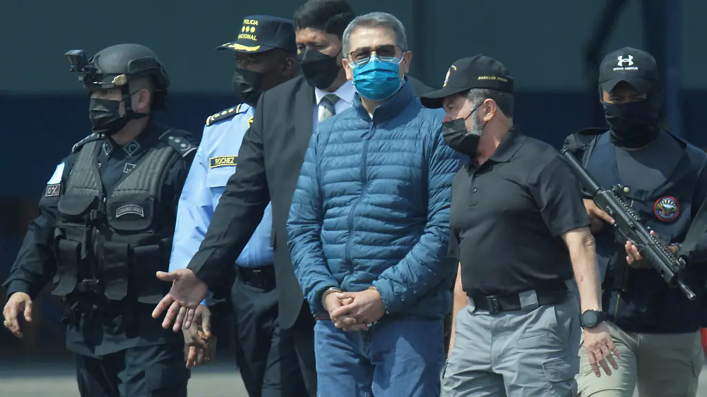 Honduras-former-President-Juan-Orlando-Hernandez-is-escorted-by-authorities-as-he-walks-towards-a-plane-of-the-U-S-Drug-Enforcement-Administration-DEA-for-his-extradition-to-the-United-States-to-face-a-trial-on-drug-trafficking-and-arms-possession-charges-at-the-Hernan-Acosta-Mejia-Air-Force-base-in-Tegucigalpa-Honduras-April-21-2022
