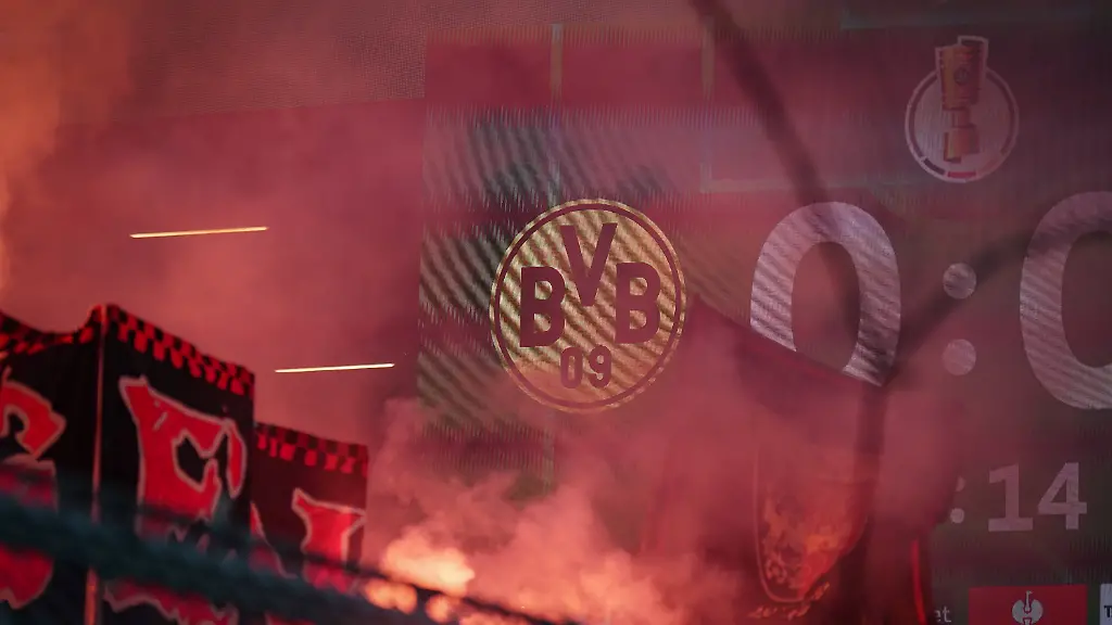 Deutschland-Fussball-DFB-Pokal-2025-26-Achtelfinale-Borussia-Dortmund-vs-Bayer-04-Leverkusen-Signal-Iduna-Park-Dortmund-Pyro-in-der-Kurve-rotleuchtender-Rauch-vor-BVB-Logo-und-DFB-Pokal-Anzeigetafel-Fankurven-Dynamik-Ultras-Fankultur-Derbyhitze-Emotionen-Sicherheitsdebatte-Stadionsicherheit-Fanproteste-Bundesliga-nationale-Pokalrunde-Identitaet-Tradition-Atmosphaere-Stadionpolitik-Medienfokus-Grossevent-Zuschauerstimmung