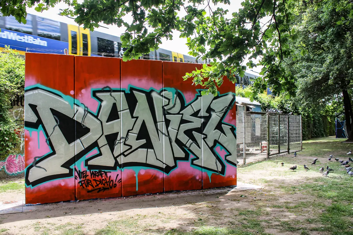 Ein-Graffiti-mit-dem-Namen-Daniel-in-einer-Gruenanlage-in-Bielefeld-zum-Gedenken-an-einen-jungen-Mann-der-bei-einer-Messerattacke-vor-der-Cutie-Bar-am-Sonntag-dem-18-05-2025-zusammen-mit-drei-anderen-jungen-Menschen-mutmasslich-von-einem-35-jaehrigen-Syrer-schwer-verletzt-wurde-Foto-vom-23-05-2025-Knapp-eine-Woche-nach-dem-Messerangriff-in-Bielefeld-hat-eine-Gruppierung-aus-dem-rechten-Spektrum-fuer-Samstag-einen-Aufmarsch-mit-Mahnwache-in-der-Stadt-angekuendigt-Dazu-wuerden-200-Teilnehmer-erwartet-teilte-die-Polizei-Bielefeld-am-Freitag-mit-Die-angemeldete-Versammlung-soll-vor-dem-Tatort-der-Tanzbar-Cuties-stattfinden-Das-Motto-der-rechtsgerichteten-Kundgebung-lautet-Anteilnahme-fuer-die-Opfer-vom-18-05-2025-und-Remigration-Ein-Bielefelder-Buendnis-rief-zu-einer-Gegendemonstration-unter-dem-Motto-Gegen-Hass-und-Hetze-in-Bielefeld-auf-Dazu-sind-laut-Polizei-500-Teilnehmerinnen-und-Teilnehmer-angemeldet-Man-sei-mit-verstaerkten-Kraeften-im-Einsatz-und-gehe-von-einem-friedlichen-Verlauf-der-Versammlungen-aus-erklaerte-das-Polizeipraesidium-Bielefeld-Siehe-epd-Meldung-vom-23-05