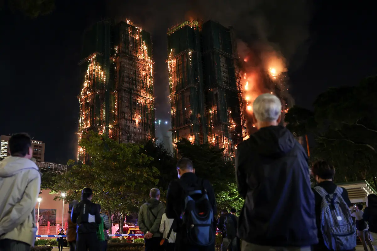 People-watch-the-flames-and-thick-smoke-rising-from-multiple-residential-blocks-at-the-Wang-Fuk-Court-housing-complex-during-a-deadly-fire-in-Tai-Po-Hong-Kong-China-November-26-2025-REUTERS-Tyrone-Siu-SEARCH-HONG-KONG-FIRE-PICTURE-FOR-THIS-STORY-SEARCH-WIDER-IMAGE-FOR-ALL-STORIES