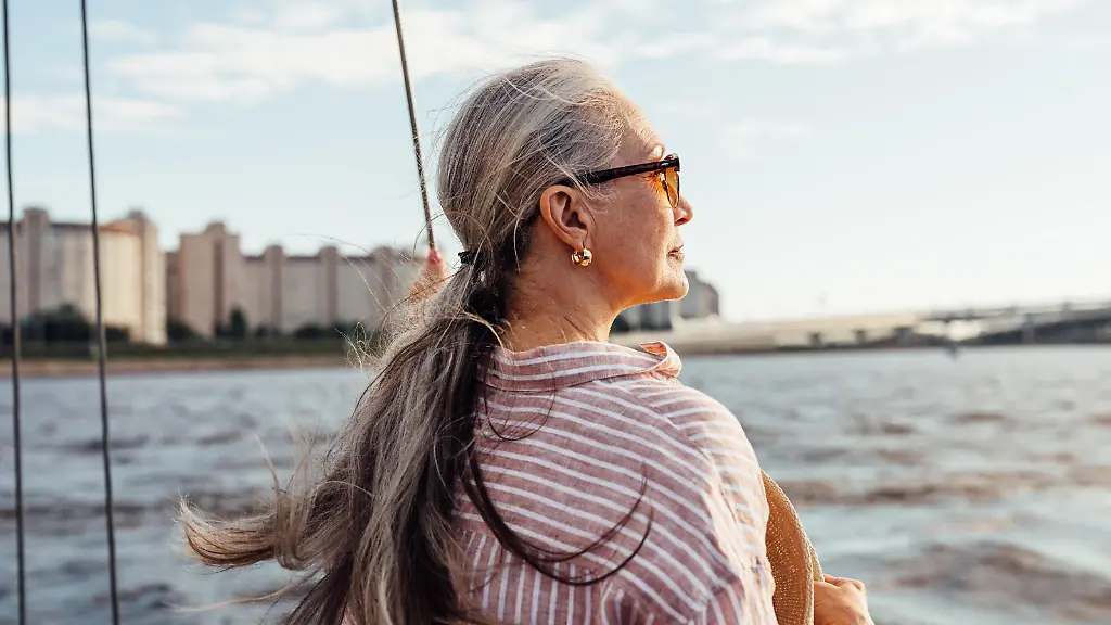 Side-view-of-mature-woman-wearing-sunglasses-and-looking-to-the-distance-while-standing-on-the-yacht-Modellfreigabe-vorhanden