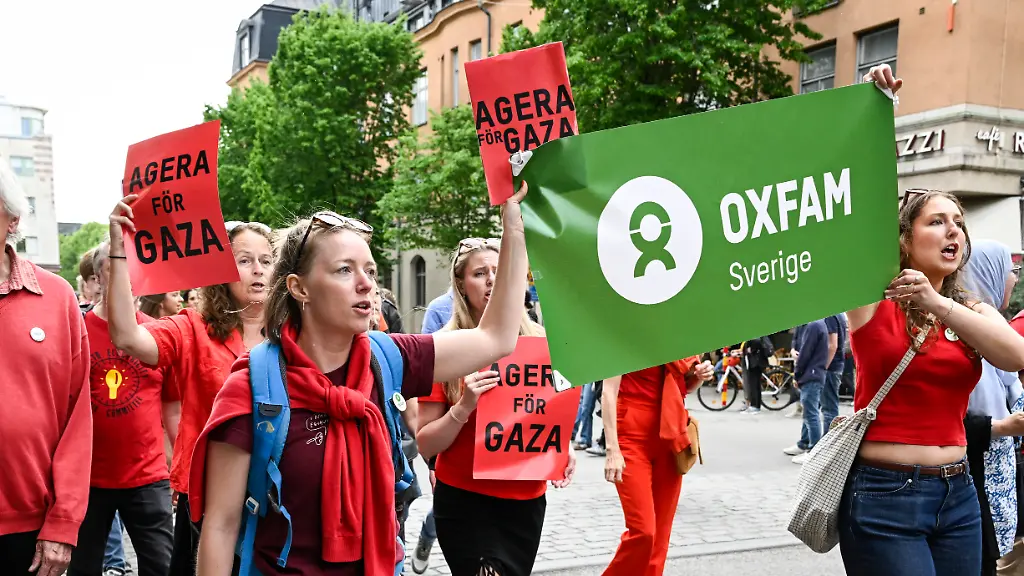 STOCKHOLM-SVERIGE-20250617-Demonstranter-klaedda-i-roett-under-en-demonstration-foer-Gaza-i-Stockholm-Demonstrationen-gar-fran-Norra-Bantorget-till-Gustav-Adolfs-torg-och-utrikesdepartementet-och-aer-arrangerad-av-Amnesty-Sverige-Oxfam-Sverige-Svenska-Freds-och-Skiljedomsfoereningen-Olof-Palmes-Internationella-Center-Act-Svenska-kyrkan