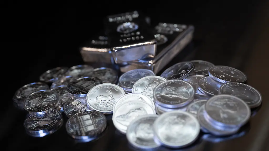 Silberbarren-und-Muenzen-Wiener-Philharmoniker-und-Kruegerrand-in-unterschiedlicher-Groesse-liegen-beim-Edelmetallhaendler-Pro-Aurum-in-einem-Tresor-auf-einem-Tisch