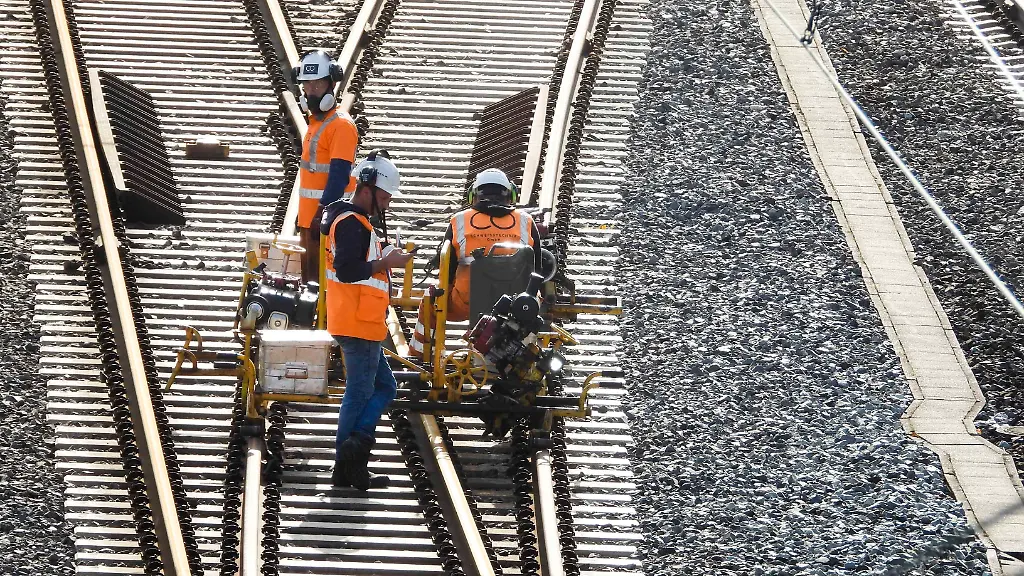 CNTV-BAHNSANIERUNG-Arbeiter-der-DB-Bahn-arbeiten-mit-Orangenen-Schutzwesten-und-Schutzhelmen-an-neuen-Gleisen-verlegen-Schienen-und-Betonschwellen