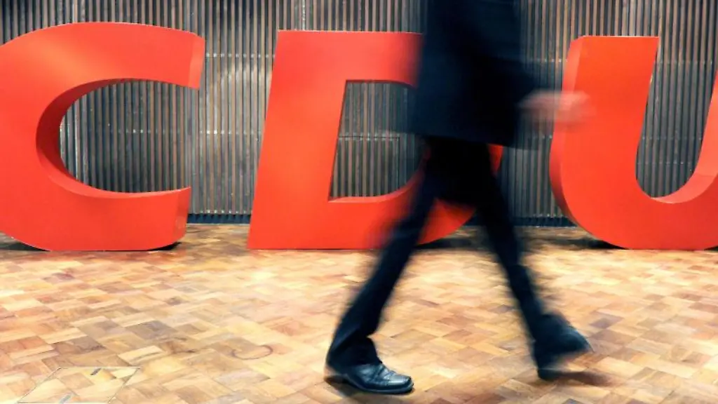 Ein-Delegierter-geht-an-einem-CDU-Logo-vorbei