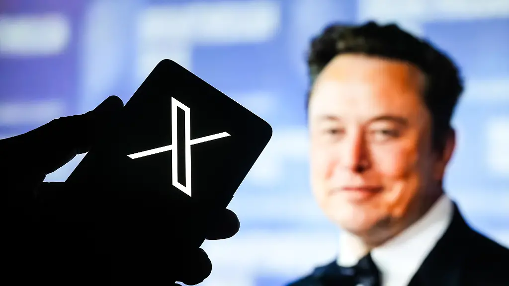 July-4-2025-Ahmedabad-Gujarat-India-In-this-photo-illustration-an-X-logo-application-is-prominently-displayed-on-a-smartphone-screen-with-Mr-Elon-Musk-in-the-background