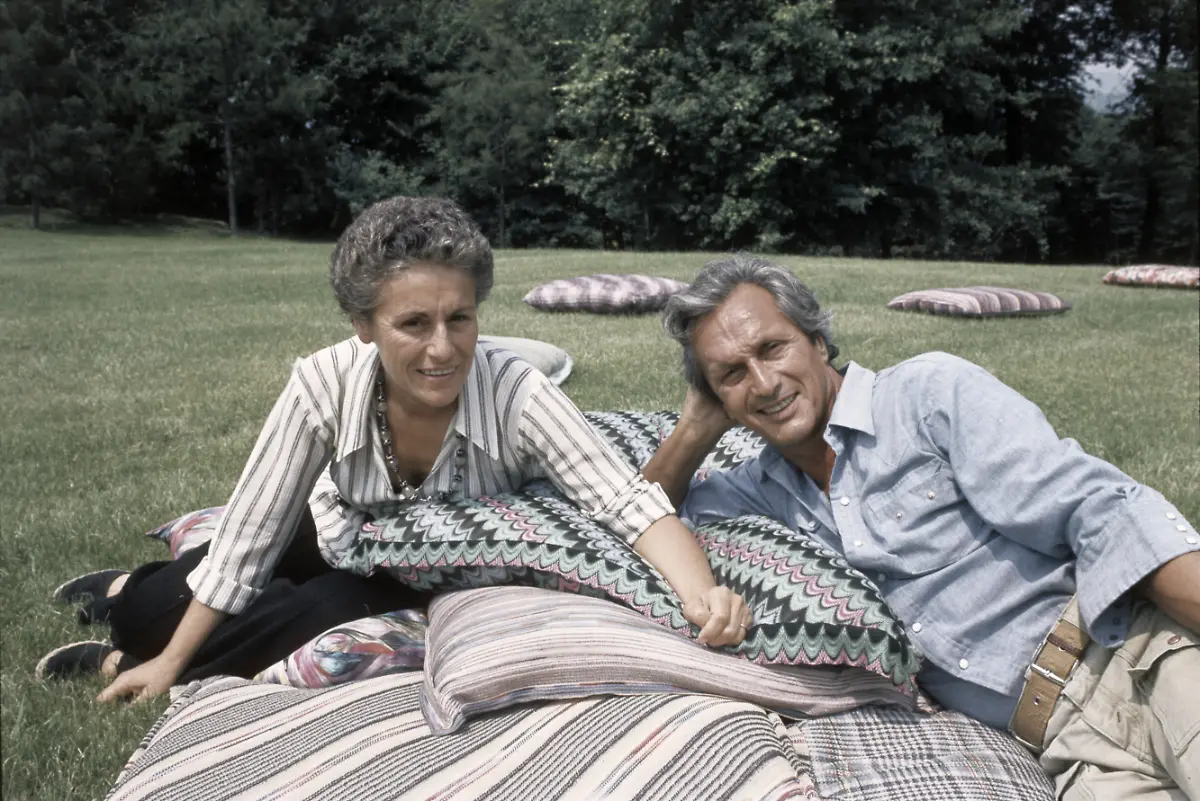 The-Italian-fashion-designer-Ottavio-Missoni-Rosita-Missions-Rosita-Jelmini-and-his-wife-sitting-on-the-lawn-of-their-mansion-They-are-leaning-over-to-big-pillows-made-A-A-from-their-tissues-Sumirago-Varese-Italy-July-1975