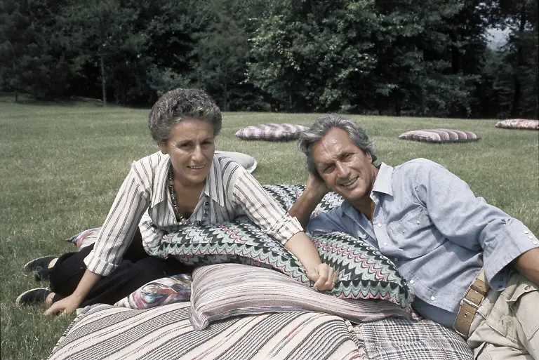 The-Italian-fashion-designer-Ottavio-Missoni-Rosita-Missions-Rosita-Jelmini-and-his-wife-sitting-on-the-lawn-of-their-mansion-They-are-leaning-over-to-big-pillows-made-A-A-from-their-tissues-Sumirago-Varese-Italy-July-1975