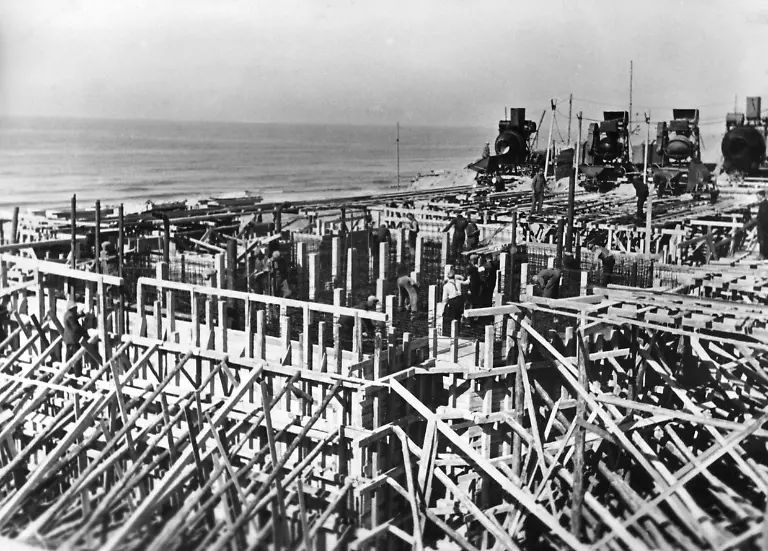 Ein-deutscher-Bunker-entsteht-am-Atlantikwall-Im-Hintergrund-sind-Betonmischer-zu-erkennen-bereit-um-die-Holzumschachtelung-und-die-Stahlgeflechte-auszufuellen-Die-Arbeitskraefte-bestehen-z-T-aus-Zivilisten