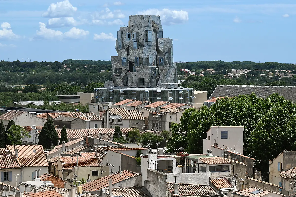 A-twisting-tower-clad-in-reflective-aluminum-tiles-designed-by-Canadian-American-architect-Frank-Gehry-and-housing-the-Luma-Foundation-is-pictured-on-June-24-2021-in-Arles-southern-France-The-Luma-Foundation-is-located-at-the-Parc-des-Ateliers-a-former-SNCF-railway-workshop-turned-into-an-open-campus-for-creative-production-display-study-and-preservation