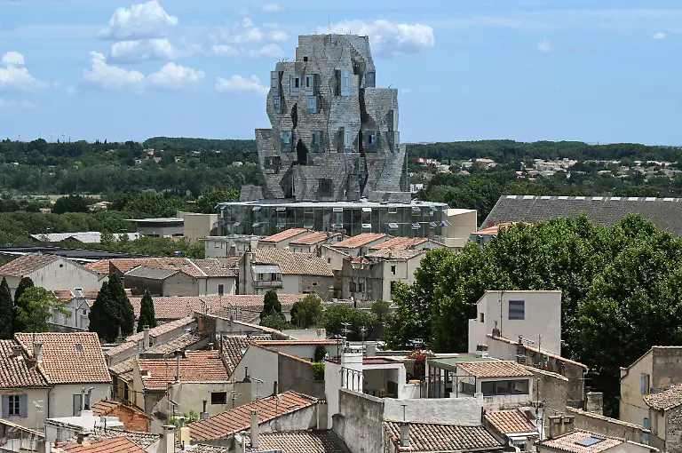 A-twisting-tower-clad-in-reflective-aluminum-tiles-designed-by-Canadian-American-architect-Frank-Gehry-and-housing-the-Luma-Foundation-is-pictured-on-June-24-2021-in-Arles-southern-France-The-Luma-Foundation-is-located-at-the-Parc-des-Ateliers-a-former-SNCF-railway-workshop-turned-into-an-open-campus-for-creative-production-display-study-and-preservation