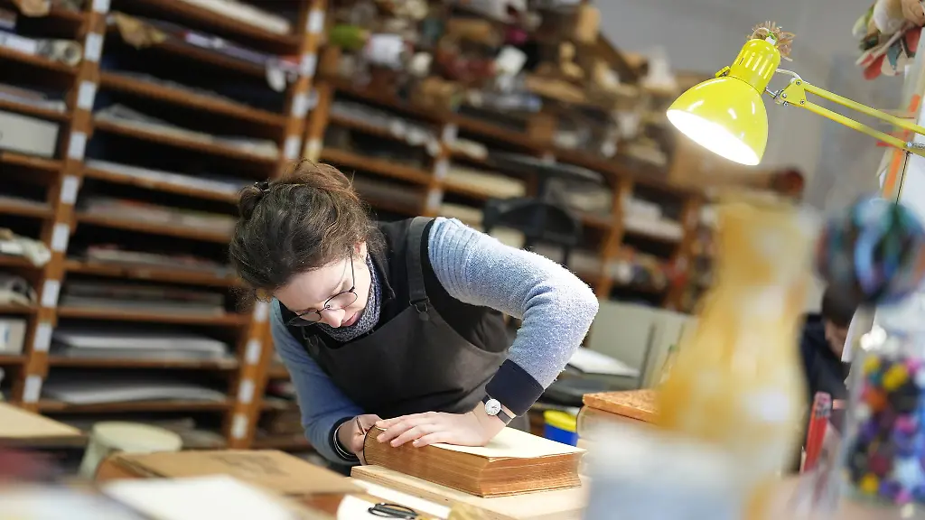 Buchbinderin-Moiken-Petong-restauriert-in-der-Werkstatt-der-Buchbinderei-Fritz-Castagne-ein-altes-Buch