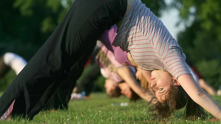 Yoga unter Anleitung auf der grünen Wiese: Angst und Depressionen schwinden.