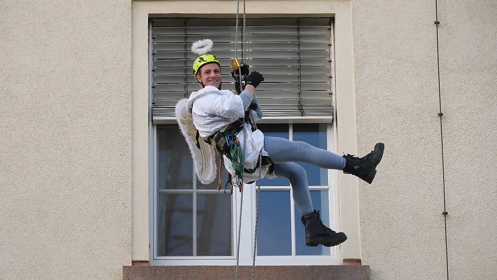 Ein-Kamerad-der-Hoehenrettung-der-Chemnitzer-Feuerwehr-seilt-sich-im-Weihnachtsengel-Kostuem-an-der-Fassade-des-Klinikums-Chemnitz-ab