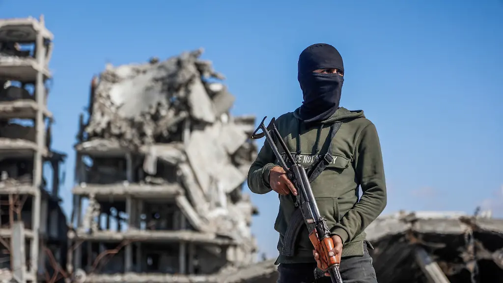 Palestinian-Hamas-militant-stands-guard-as-Egyptian-workers-accompanied-by-members-of-the-International-Committee-of-the-Red-Cross-ICRC-use-a-digger-as-they-search-for-the-last-two-remaining-bodies-of-hostages-an-Israeli-soldier-and-a-Thai-national-from-under-the-rubble-of-the-Jabalia-refugee-camp-in-the-northern-of-Gaza-Strip-on-December-1-2025-The-Gaza-war-was-sparked-by-Hamas-s-October-7-2023-attack-on-Israel-resulting-in-the-deaths-of-1-221-people-and-the-taking-251-hostage-Israel-s-retaliatory-assault-on-Gaza-has-killed-over-70-000-people-according-to-figures-from-the-health-ministry-that-the-UN-considers-reliable