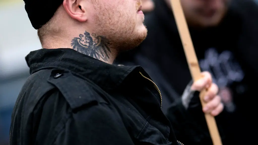 DEU-Deutschland-Germany-Berlin-29-11-2025-Demonstrant-mit-Tattoo-Symbol-Reichsadler-bei-dem-Marsch-Kundgebung-und-Demonstration-der-rechtsextremen-Partei-Die-Heimat-ehemals-NPD-unter-dem-Motto-Betrueger-und-Kriminelle-Auslaender-raus-und-Heimatschuetzer-in-Berlin-Deutschland-Neben-Mitgliedern-der-Heimat-und-der-Jugendorganisation-Junge-Nationalisten-JN-fanden-sich-auch-Mitglieder-Deutsche-Jugend-Voran-DJV-und-der-sog-Jaegergruppe-Jaegergruppe-Ein-breites-Buendnis-von-der-antifaschistischen-Aktion-antifa-bis-zu-Omas-gegen-rechts-konnte-mit-einer-Blockade-die-eigentliche-Demo-verhindern-en-Protester-with-tattoo-symbol-imperial-eagle-Reichsadler-at-the-march-and-demonstration-of-the-far-right-party-Die-Heimat-formerly-NPD-under-the-motto-Cheaters-and-Criminals-Foreigners-Out-and-Homeland-Protectors-in-Berlin-Germany-Besides-members-of-the-Heimat-youth-organization-Young-Nationalists-Junge-Nationalisten-JN-members-of-the-Deutsche-Jugend-Voran-German-Youth-Forward-DJV-and-the-so-called-Hunter-Group-Jaegergruppe-were-also-present-A-broad-alliance-ranging-from-the-anti-fascist-action-group-Antifa-to-Grandmas-Against-the-Right-successfully-blocked-the-demonstration